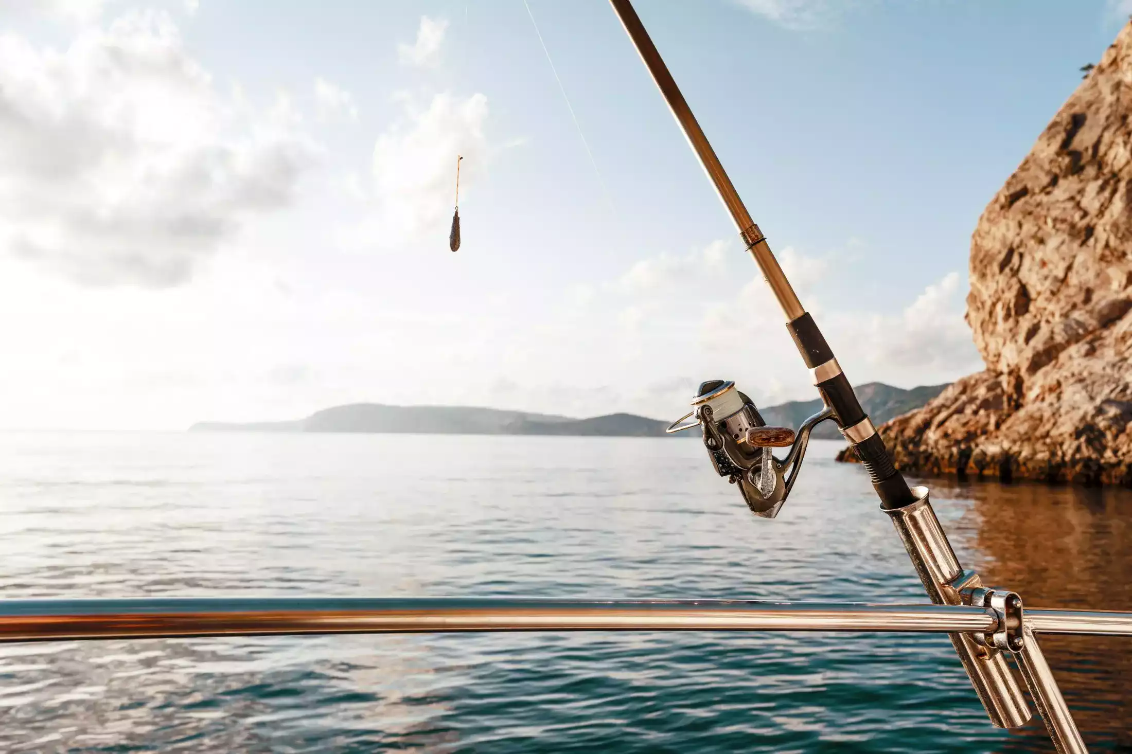 Fishing rod on a sailboat floating the ocean.